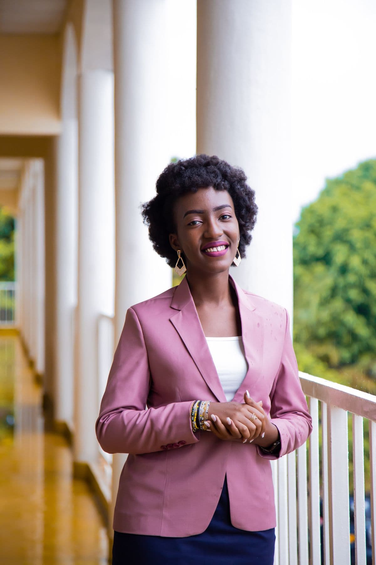 A person smiling confidently outdoors on a covered balcony
