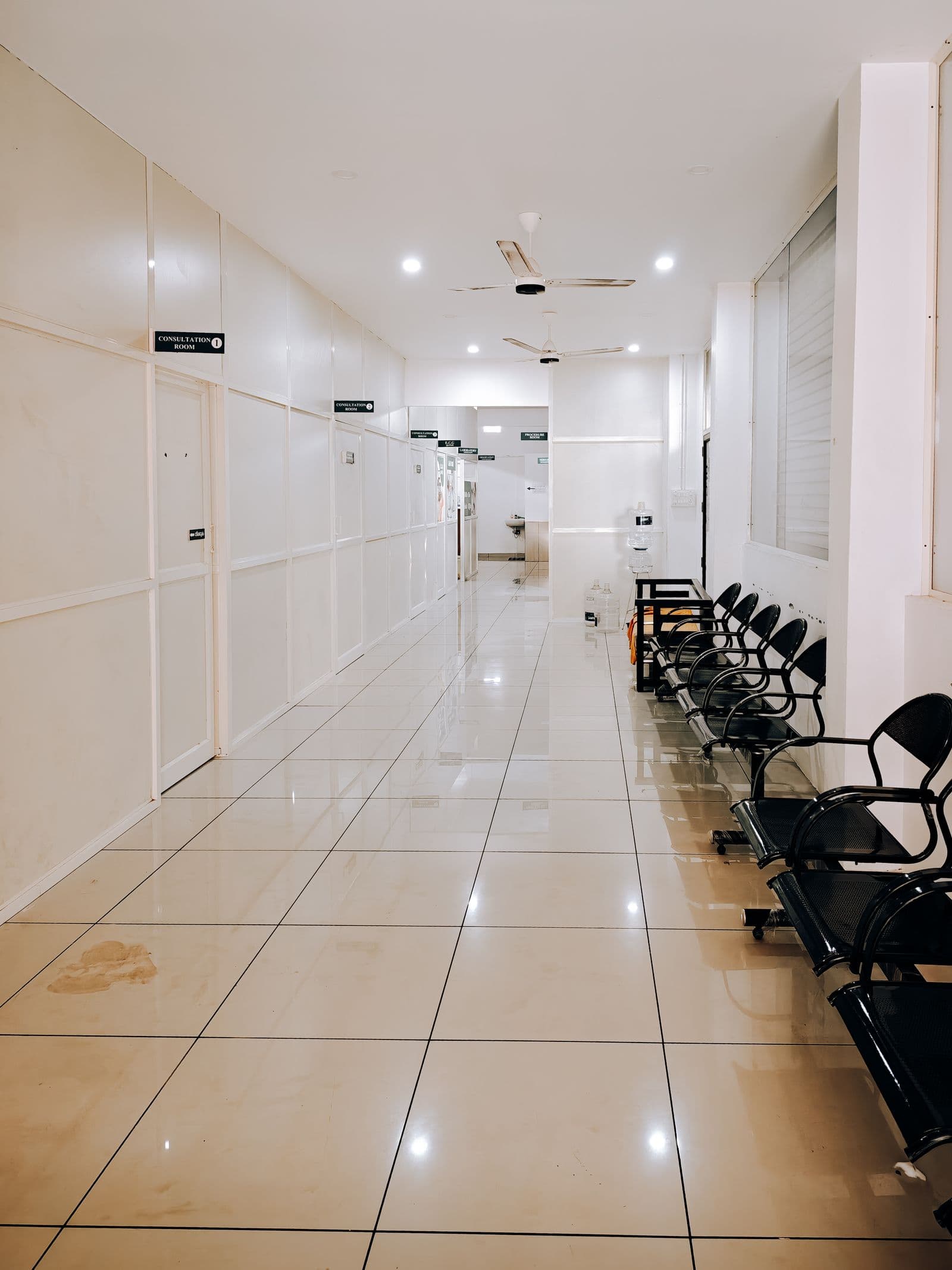 A clean, minimal clinic corridor with seating outside consultation rooms