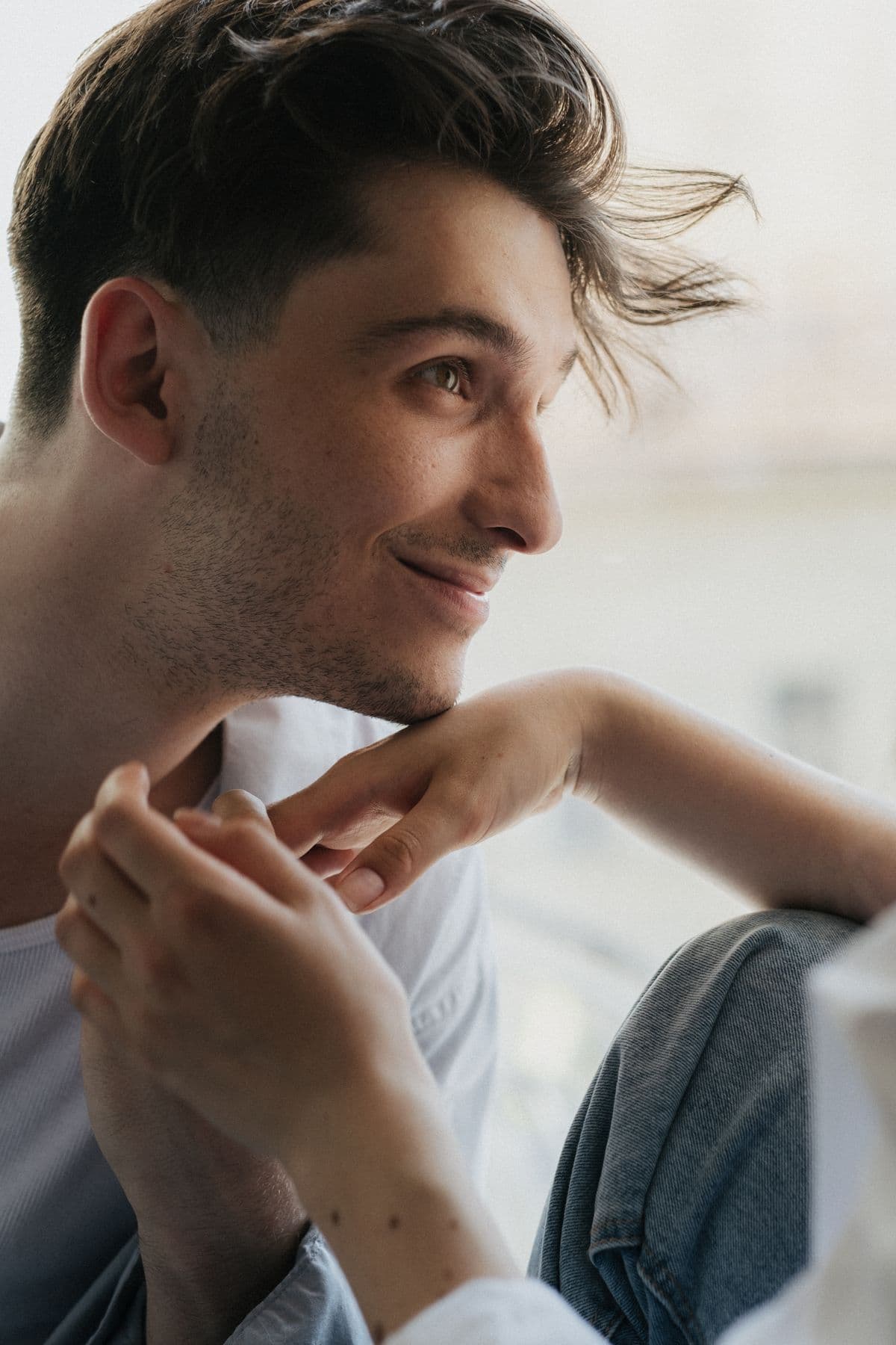 An adult man with a relaxed, confident smile in soft natural light