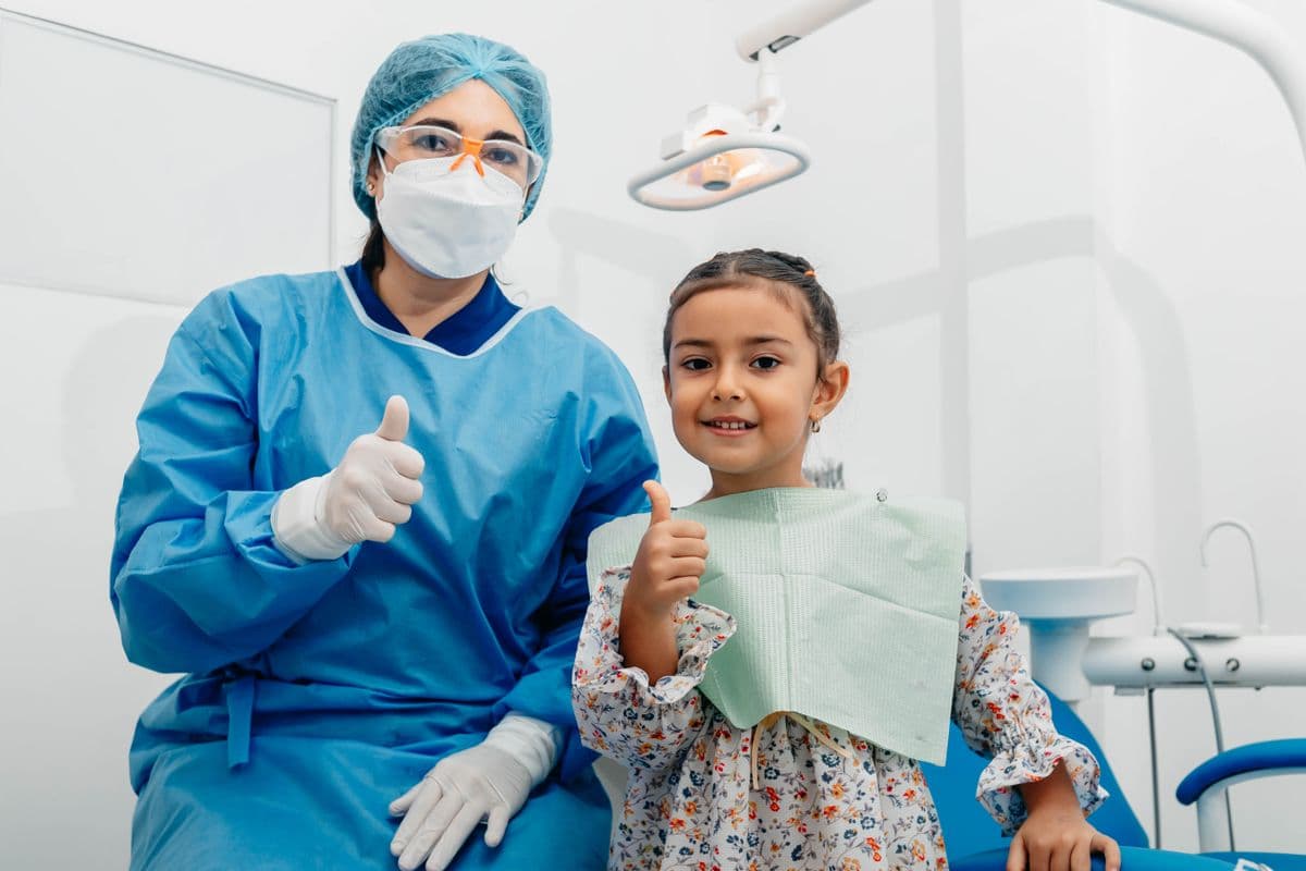A young patient and a clinical assistant giving a thumbs up together in a dental clinic